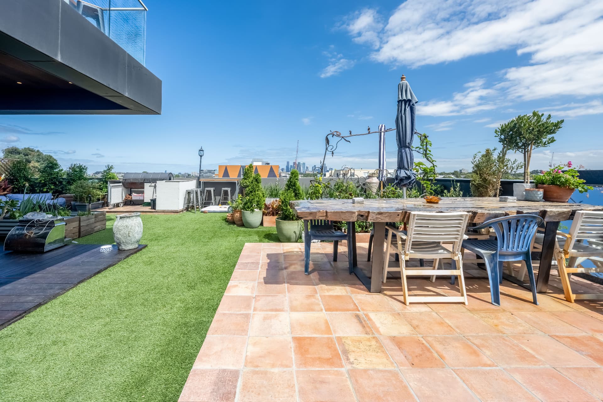 Private rooftop terrace with long timber table and the Melbourne skyline beyond